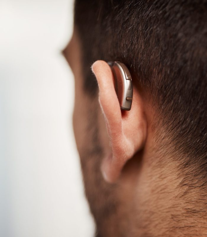 Closeup of hearing aid, ear and man with disability from the back for medical support, listening or.